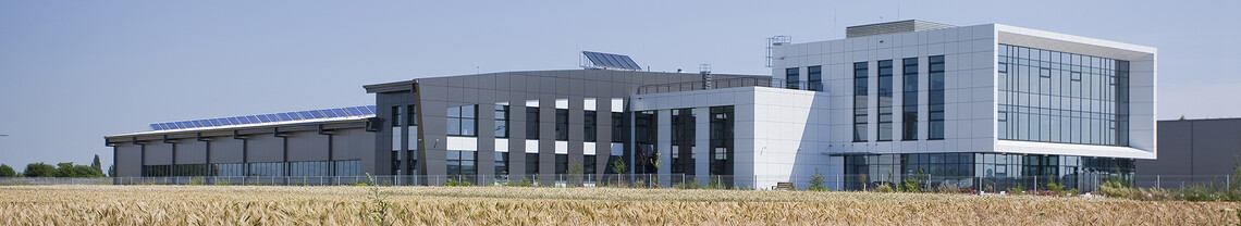 hellgraues Produktionsgebäude mit Glas neben Feld